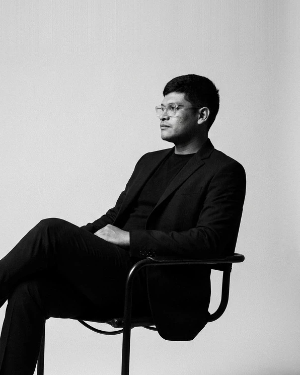 Shaheed Gqokoma, founder of Creative OS, seated in a black suit, in black and white