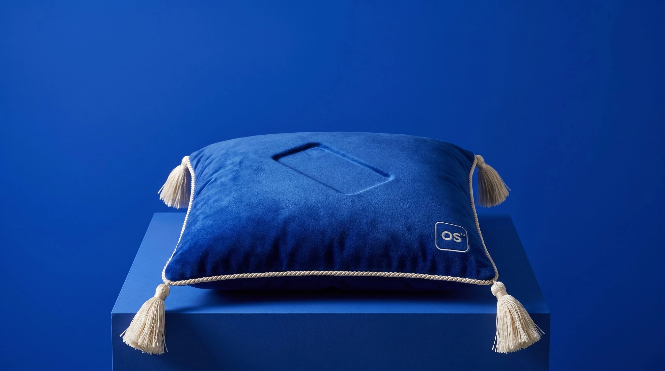 An empty cobalt velvet cushion holding the impression of a phone